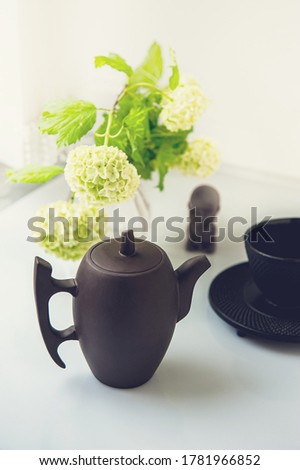 Cup of tea with white flowers on a light background. Mocap for postcards. Spring. beautiful teapot. A copy of the space. the concept of holidays and wishes of good morning