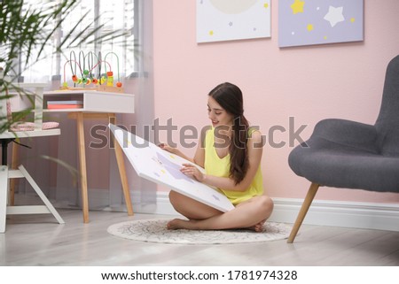 Decorator with picture near pink wall indoors. Children's room interior design