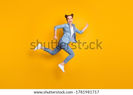 Full body profile photo of attractive teen lady jump up run race marathon excited to win rushing competitive participant wear casual denim shirt sneakers isolated yellow color background