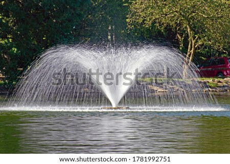 A public park fountain in a pond using a slow shutter speed to give the water a smooth lacy effect.