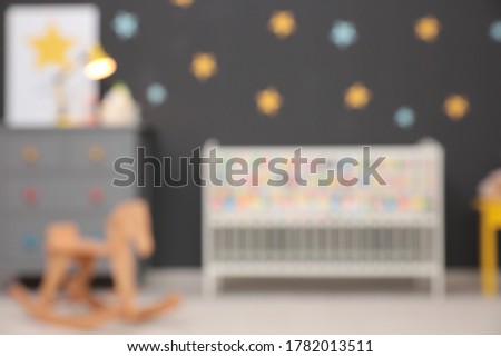 Blurred view of cute baby room interior with modern crib and rocking horse