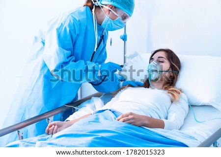Doctor examining female patient in critical health conditions using a stethoscope in the intensive care unit of a modern hospital during covid-19 pandemic Royalty-Free Stock Photo #1782015323