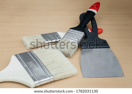 Tool for painting work. Spatula and brushes. Set of items for repair. Top view of a builder with a brush and spatula for applying putty on wood. 