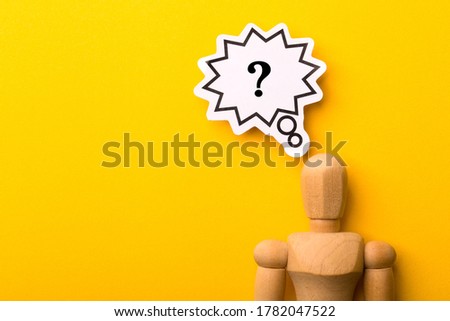 Wooden man with question mark speech bubble on yellow background.