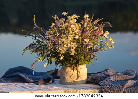 Still life with bouquet of wild flowers on a background of river	