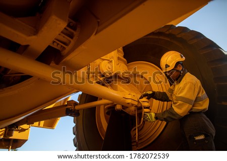Safety workplace pre operation checklist motor vehicle mechanic inspector wearing safety glove helmet head protect inspecting haul truck bolts and nuts steering wheel connection prior work each shift 
