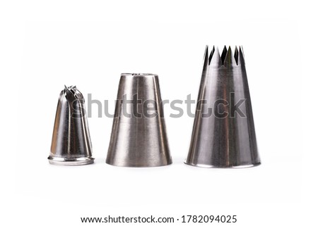 Different sized and shaped stainless steel toothed piping bag tips for decorating pastry isolated on white background
