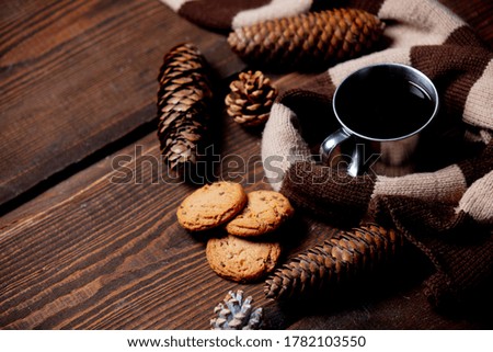 Cup of coffee with cookies and scarf on wooden table