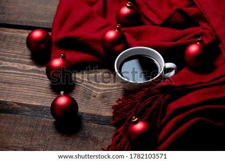 Cup of coffee with Christmas baubles and scarf on wooden table