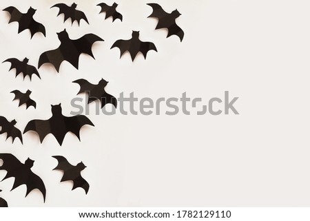 Halloween holiday decorations of many paper bats flying over an empty white background with free space for text. Top view.