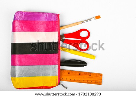 multicolored pencil case and school supplies on flat lay