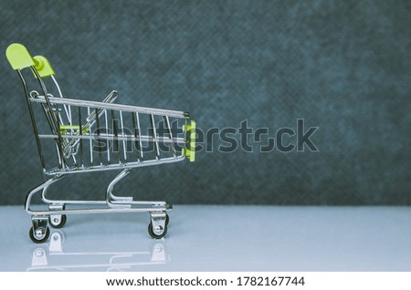 Shopping cart in green on a blurred background. Close-up. Shopping trip concept.