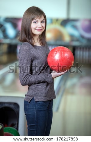 Young beautiful smiling girl playing bowling
