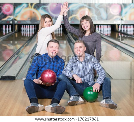 Funny young people smiling at the camera playing bowling