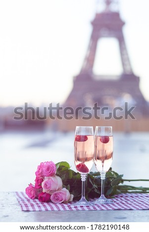 Beautiful, romantic, elegant proposal on Saint Valentine's day in Paris - city of love. Bouquet of pink roses, two glasses of wine, raspberry. Eiffel tower on background. Close up copy space. Tonned