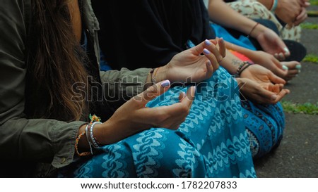 Photograph of the hands of people sitting in a lotus pose at an Indonesian ceremony handed over by aromotic sticks and baskets with flowers