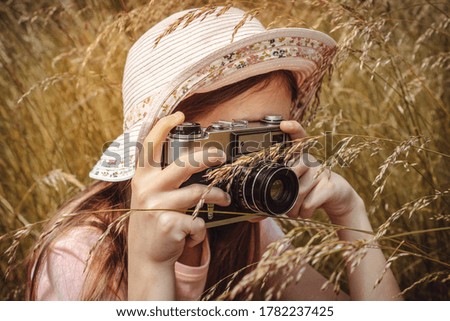Girl taking photo outdoors with old camera. Selective focus at lens, unrecognizable person. Lifestyle portrait, soft toned