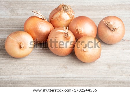 A bunch of fresh, authentic sweet southern-grown onions artfully arranged on a white painted rustic wood panel board.