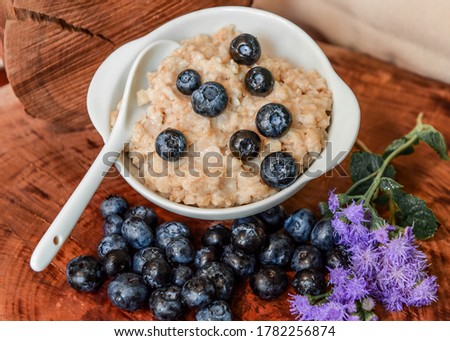 Oatmeal with blueberries. Healthy breakfast. Wooden background. Top view. Selective soft focus. Shallow depth of field.