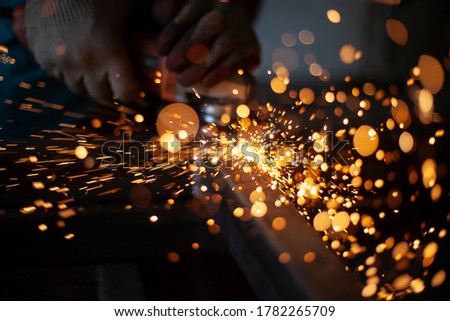 Work with a grinder for metal. Sparks from metal friction. A worker is grinding a part. Steel processing with an electric tool. Creation of the structure in the workshop. Royalty-Free Stock Photo #1782265709