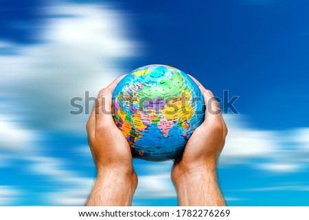 Conceptual symbol human hands surrounding the Earth world globe. the sky is in motion