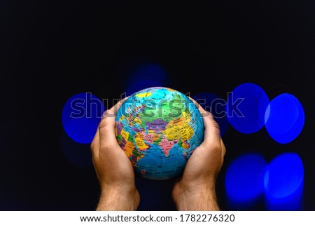 Planet Globe Earth in the hands of man against the colored lamps blurred. Concept on business, politics, ecology and media. Earth night abstract background.
