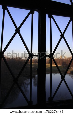 
window of a castle overlooking the lake and sunset