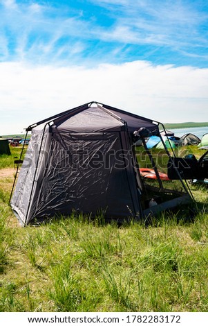 Gray camping tent in green grass. Camping area in nature.
