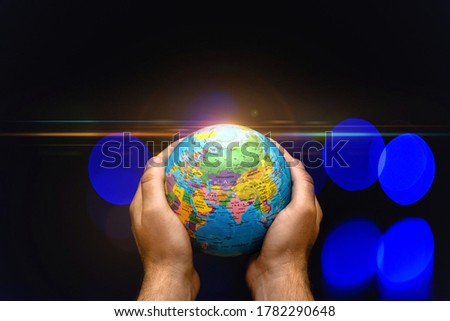 Planet Globe Earth in the hands of man against the colored lamps blurred. Concept on business, politics, ecology and media. Earth night abstract background.