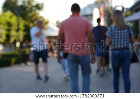 Blurred background. A group of people on a city street. The view from the back.