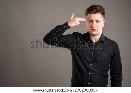 Portrait of serious stylish attractive man dressed with a casual black shirt shot head gesture isolated on gray background with copy space advertising area