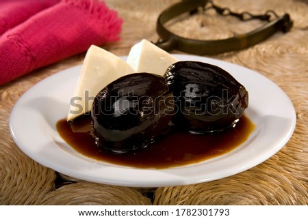Traditional Ecuadorian dish "Higos con Queso", or Figs with Cheese, on a white plate and wicker table. Food still life. Royalty-Free Stock Photo #1782301793