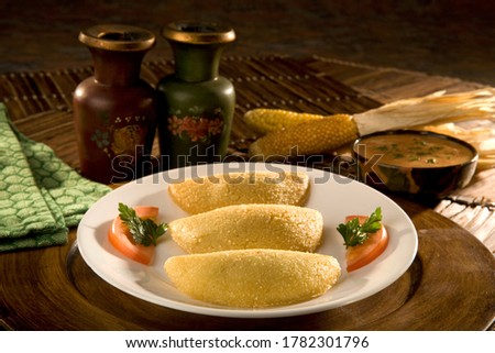 Empanadas de morocho are a traditional style of Ecuadorian empanadas, a turnover pastry mold, fried and filled with rice, corn, and beef and vegetables. With homemade hot sauce. Food still life. Royalty-Free Stock Photo #1782301796