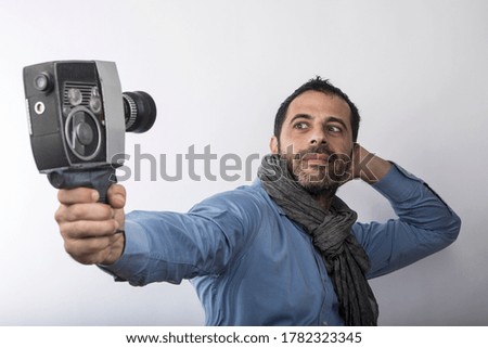 man with blue shirt and scarf uses his vintage movie camera, isolated on light background