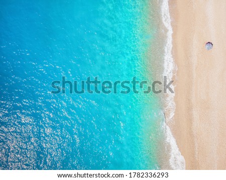 Beach holiday concept with a lonely umbrella on soft toned pebbles against emerald and turqoise ocean and with copy space Royalty-Free Stock Photo #1782336293
