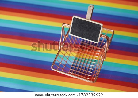 Black board with wooden details attached in the vintage supermarket basket. Rainbow surface. Price tag.             