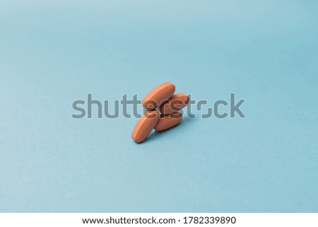Stock photo of orange pills on a blue background. There is nobody on the picture.