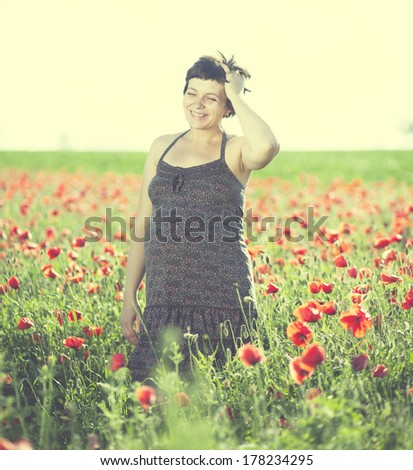 Vintage photo of pregnant happy woman in a flowering poppy field outdoors