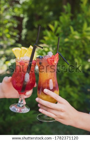 summer fruit cocktails in gentle female hands on the background of nature
