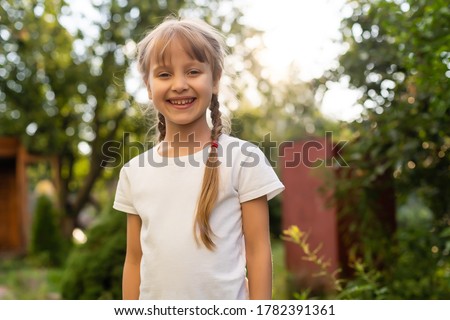 Beautiful little blonde girl with long hair in white T-shirt smiling