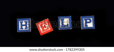 Wooden block letters spell the word help on black background.