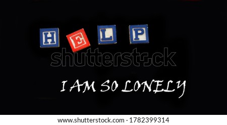Wooden block letters spell the word help.  Below message says I am so lonely.  Board is rimmed with primary colors.