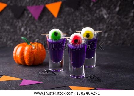 Halloween drink. Purple shot cocktail decorated with eyes.
