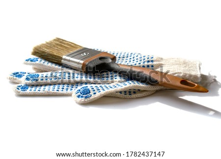 paint brush on top of brand new construction gloves. White background. construction and renovation concept.
