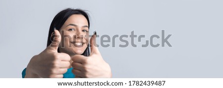 Happy young caucasian female in a blue t-shirt making thumb up sign and smiling. Good job and respect.