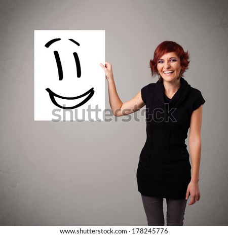 Attractive young woman holding smiley face drawing