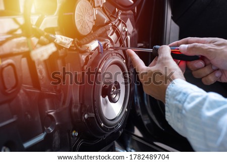 Technician installing the car speaker to the car door. Car audio installation concept. Royalty-Free Stock Photo #1782489704