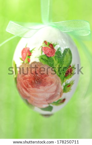 Easter egg decorated with flowers made by decoupage technique on green background