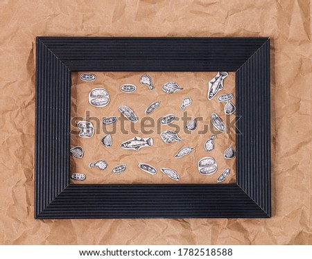 Collage of fast food items in a black frame on crumpled paper, top view close-up.