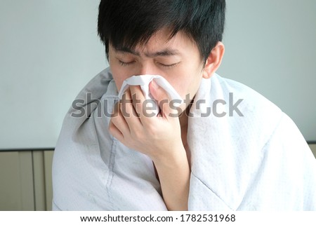 Sick man is flu, using a paper napkin and he have a runny nose. And he was covered in warm cloth.Health concept